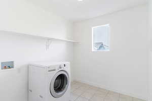 Clothes washing area featuring washer / dryer and light tile patterned floors