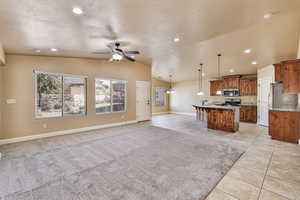 Kitchen featuring ceiling fan, stainless steel appliances, an island with sink, lofted ceiling, and decorative pendant lights