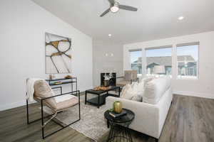 Living room with ceiling fan, dark wood-type flooring, and vaulted ceiling