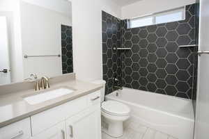 Full bathroom with toilet, vanity, and tiled shower / bath