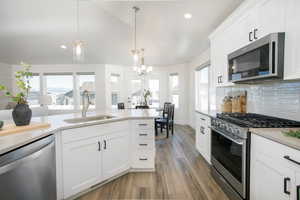 Kitchen featuring decorative backsplash, appliances with stainless steel finishes, sink, decorative light fixtures, and an inviting chandelier