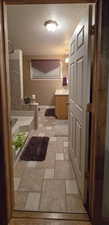 Full Primary bathroom with stone tile floors, a shower, a textured ceiling, vanity, and a bath