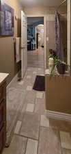 Full Primary bathroom with a textured ceiling, baseboards, tiled shower, and vanity