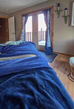 Primary bedroom featuring access to exterior, wood finished floors, and baseboards