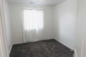 Unfurnished room featuring dark carpet