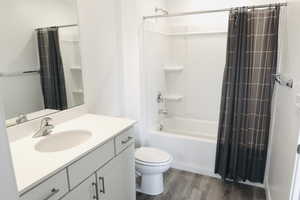 Full master bathroom with hardwood / wood-style floors, vanity, toilet, and shower / bath combination with curtain