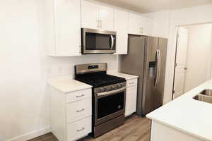 Kitchen featuring white cabinets, stainless steel appliances, and light hardwood / wood-style floors