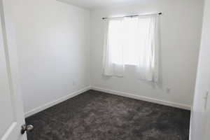 Spare room featuring dark carpet