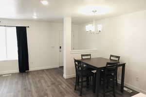 Dining space with dark hardwood / wood-style flooring and a notable chandelier