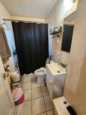 Bathroom featuring toilet, vanity, tile patterned floors, and walk in shower