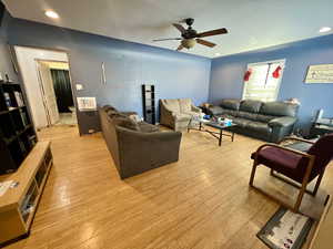 Living room with ceiling fan and light hardwood / wood-style floors