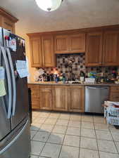 Kitchen with stainless steel appliances, tasteful backsplash, and light tile patterned flooring