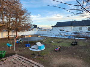 View of yard with a playground and a trampoline