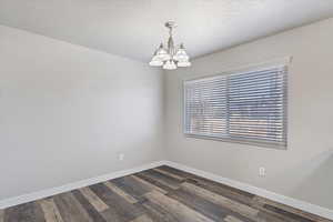 Dining dark hardwood / wood-style flooring, a textured ceiling, and a chandelier