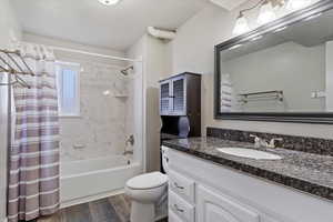 Full bathroom featuring shower / bath combination with curtain, vanity, hardwood / wood-style flooring, and toilet