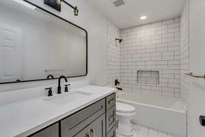 Full bathroom featuring toilet, tile patterned flooring, vanity, and tiled shower / bath