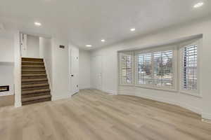 Unfurnished living room featuring ornamental molding and light hardwood / wood-style flooring