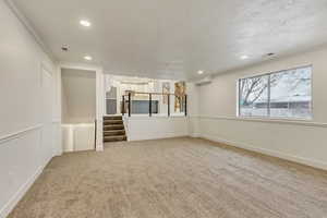 Unfurnished living room featuring carpet and ornamental molding