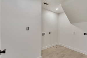 Clothes washing area with hookup for a washing machine, light wood-type flooring, and hookup for an electric dryer