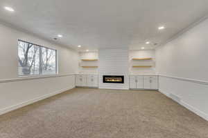 Unfurnished living room with crown molding, a fireplace, and light carpet