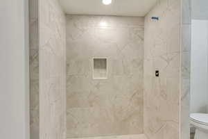 Bathroom featuring toilet and tiled shower