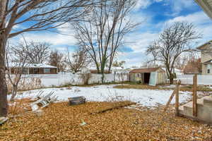 Yard covered in snow featuring a storage shed