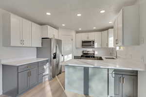 Kitchen featuring sink, white cabinets, appliances with stainless steel finishes, and gray cabinetry