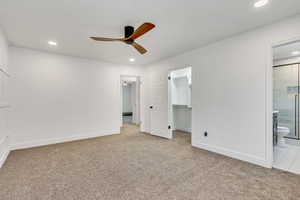 Unfurnished bedroom with a closet, a walk in closet, light carpet, and ensuite bath