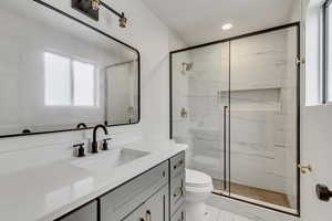 Bathroom featuring toilet, an enclosed shower, and vanity