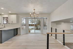 Kitchen featuring a chandelier, white cabinetry, a healthy amount of sunlight, and decorative light fixtures