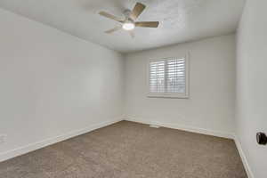 Unfurnished room featuring carpet flooring, ceiling fan, and a textured ceiling