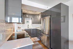 Kitchen featuring decorative backsplash, gray cabinetry, stainless steel appliances, sink, and light hardwood / wood-style flooring