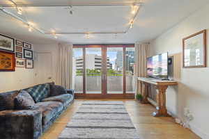 Living room with track lighting, light hardwood / wood-style flooring, and french doors