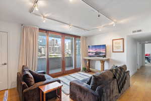 Living room featuring french doors, rail lighting, and light hardwood / wood-style flooring