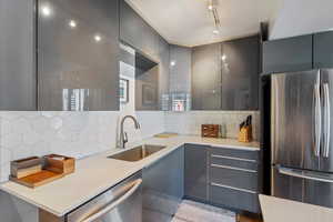 Kitchen featuring gray cabinetry, decorative backsplash, sink, and stainless steel appliances