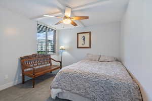 Carpeted bedroom with ceiling fan and beam ceiling