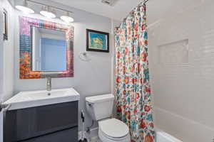 Full bathroom featuring vanity, shower / bath combination with curtain, and toilet