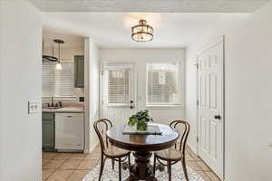 Dining space featuring sink, light tile patterned floors, and a textured ceiling