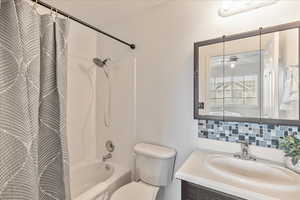 Full bathroom featuring shower / bathing tub combination, vanity, ceiling fan, toilet, and tasteful backsplash