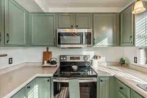 Kitchen featuring stainless steel appliances, tile patterned floors, and green cabinetry