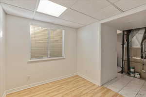 Basement with a paneled ceiling and hardwood / wood-style floors