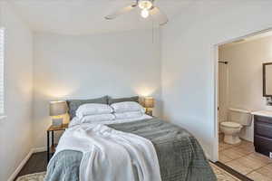 Tiled bedroom featuring ceiling fan and ensuite bathroom