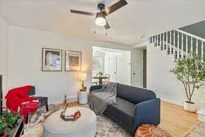 Living room with ceiling fan and hardwood / wood-style floors