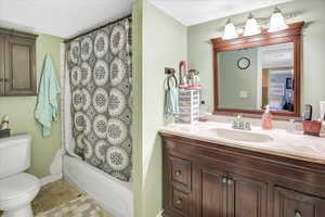 Full bathroom featuring tile patterned flooring, shower / bath combination with curtain, toilet, and vanity