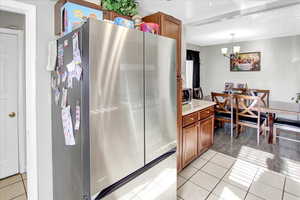 Kitchen featuring a chandelier, light tile patterned flooring, stainless steel appliances, and decorative light fixtures