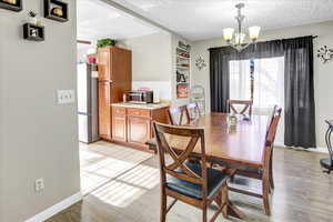 Dining room with light hardwood / wood-style floors, a textured ceiling, and a chandelier