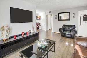 Living room with a textured ceiling and light wood-type flooring