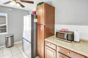 Kitchen with ceiling fan, decorative backsplash, light tile patterned floors, and stainless steel appliances