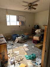 Primary bedroom featuring ceiling fan, cooling unit, a textured ceiling, with connected bathroom