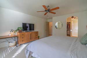 Carpeted bedroom featuring ceiling fan, a walk in closet, and a closet